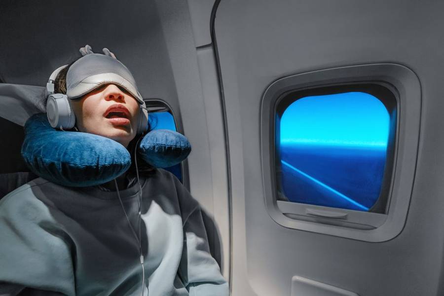 Woman with an eye mask and neck pillow sleeping on a plane