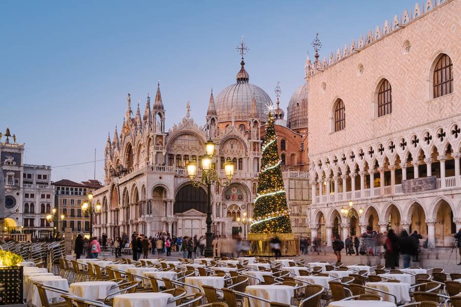 People walking in San Marco square in the evening. On the square the Christmas tree with lights and decorations in front of the Doge's Palace
