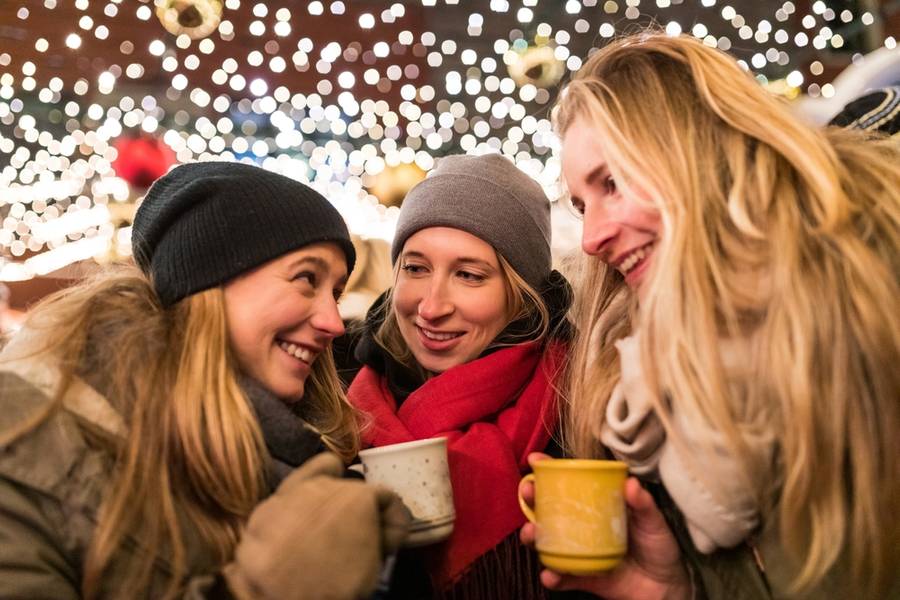 Happy young women with cups of mulled wine at Christmas market in Vienna