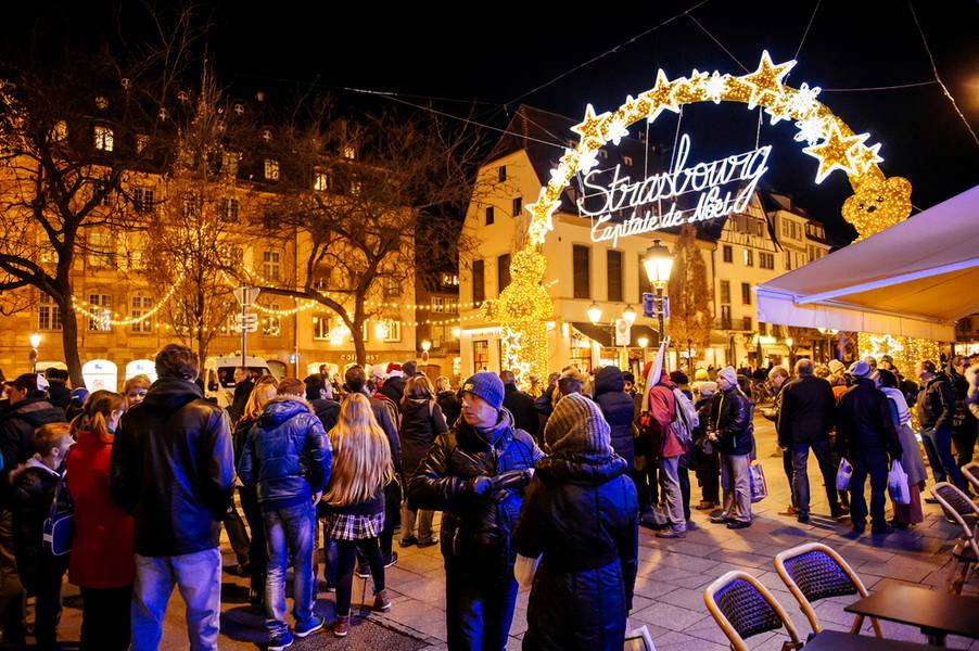 Busy Christmas Market Christkindlmarkt in the city of Strasbourg, Alsace region, France with people admiring Capitale de Noel sign 
