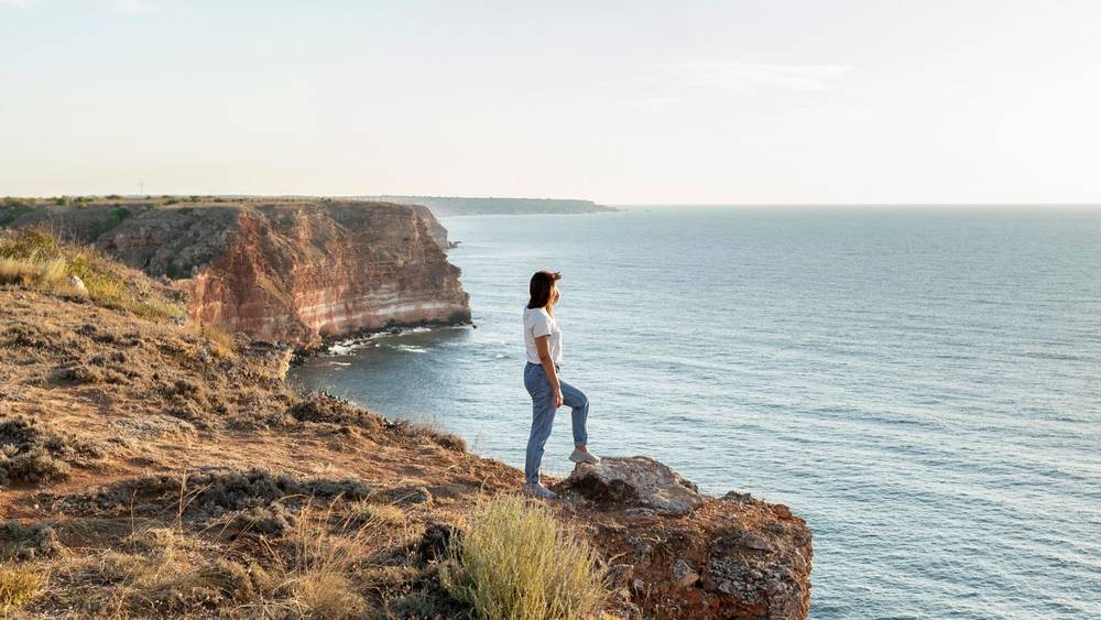 A woman standing on a cliff looking at the ocean in South Australia