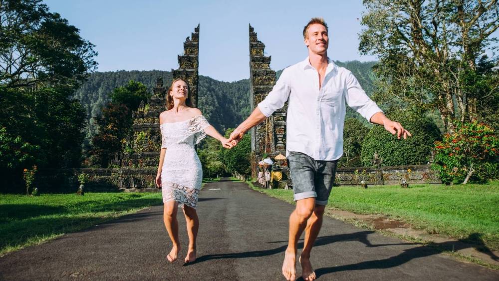 A couple running down the road in Bali in front of a gate