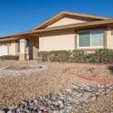 Featuring curb appeal and fully paid solar panels, this property offers energy efficiency and style. A desert landscape with gravel and a red-brick path completes the home's inviting exterior.