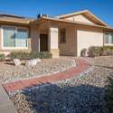 A closer look at the front entryway showcasing modern plantation shutters, a fresh stucco finish, and a thoughtfully landscaped yard, perfect for Arizona's low-maintenance lifestyle.