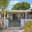 The front courtyard offers privacy and curb appeal, featuring a decorative gate, mature landscaping, and a covered patio, making for a welcoming entrance.