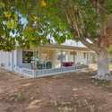 This private backyard features a mature tree for shade, a covered patio, and open space, making it a perfect place for outdoor relaxation or small gatherings.