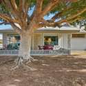 This backyard setting includes a covered patio, mature trees, and ample space, offering a relaxing outdoor retreat with beautiful views of the community.