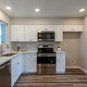 A chef s dream kitchen featuring quartz countertops, stainless steel appliances, and sleek white cabinetry. The open design creates a bright, stylish cooking space.
