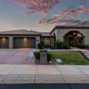 Captured at golden hour, this evening exterior shot highlights the stunning architecture, expansive garage, and manicured front landscaping. A peaceful setting in a prime Arizona location with great walk-up charm.