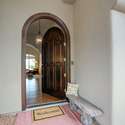 Step into style through a rounded wood door beneath an arched portico. This inviting entryway blends Mediterranean influences with Arizona elegance, setting the tone for the custom design and light-filled interiors found inside.