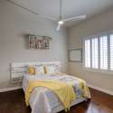 A warm and inviting guest room featuring plantation shutters, vaulted ceilings, and wood floors ideal for peaceful rest or a private reading space.