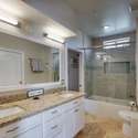 Recently updated, this bathroom features sleek granite countertops, dual sinks, stylish lighting, and a tiled shower/tub combo with a sliding glass door.
