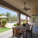 Dine outdoors year-round beneath this elegant covered patio featuring overhead fans, archways, and views of the landscaped backyard. A seamless connection to the home s interior makes entertaining effortless.