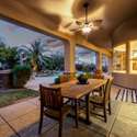 As the sun sets, this covered outdoor dining area becomes a warm and inviting gathering place. With stone accents, ceiling fans, and access to the yard and interior, it s built for stylish hosting.