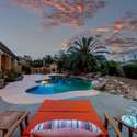 This evening view of the backyard oasis highlights a beautifully lit pool surrounded by desert palms and manicured landscaping. From peaceful lounging to vibrant gatherings, this Scottsdale space was designed for refined outdoor living.