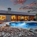 Featuring a gorgeous covered patio with architectural columns and soft ambient lighting, this backyard sets the tone for effortless entertaining. The pebble-finish pool and desert landscape offer a relaxing, energy-efficient escape.