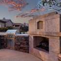Gather around this luxurious built-in fireplace and BBQ under a sky painted in sunset hues. The stonework and thoughtful layout add warmth and sophistication to this elevated outdoor living experience.