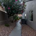 Nestled between the home and privacy walls, this side yard features mature trees, desert landscaping, and a winding path ideal for extra storage, gardening, or discreet access to the backyard.
