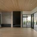 Showcasing a striking mix of textures, this light-filled living space features warm wood ceilings, expansive windows, and clean architectural lines designed for comfort and visual impact.