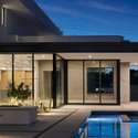 A dramatic detail shot reveals the architectural beauty of the backyard, with glowing reflections on the pool, textured concrete walls, and open-concept living extending outdoors.