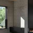 This close-up captures the minimalist sophistication of the living room s black steel fireplace and concrete feature wall ideal for energy-efficient warmth and modern appeal.