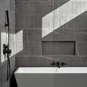 The freestanding soaking tub is framed by contemporary tile and matte black hardware, providing a private, luxurious spot for relaxing and recharging at home.