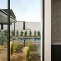 Framed by floor-to-ceiling glass, the desert landscaping and pool beyond become a daily visual treat. This tranquil hallway exemplifies the home s seamless indoor-outdoor connection.