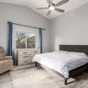 Vaulted ceilings and plush carpet create a cozy, elevated feel in this spacious primary bedroom. Ample natural light flows in through the window, creating a soothing and serene retreat in this Laveen home.