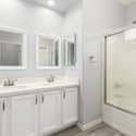 This updated ensuite bathroom includes a dual vanity with quartz counters, framed mirrors, and chrome fixtures. A full tub/shower combo adds both function and style for everyday use.