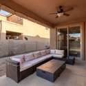 Enjoy Arizona evenings in this shaded covered patio featuring a ceiling fan, warm stucco finishes, and a cozy sectional setup. Perfect for relaxing or entertaining, the space opens seamlessly to the backyard through sliding glass doors.