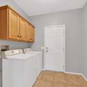 The home s interior laundry room includes a washer, dryer, and upper wood cabinets offering everyday convenience and organized storage for your short-term or seasonal stay in Surprise, Arizona.