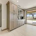 This bonus kitchen space features extensive cabinetry with glass uppers, a built-in wine fridge, and a wet bar ideal for entertaining. Premium finishes and direct patio access make this area both practical and luxurious.