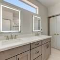 The dual-sink vanity shines with quartz countertops, under-mount sinks, and sleek LED mirrors. Paired with brushed hardware and designer faucets, this space is both elegant and functional.