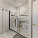 A glass-framed shower with striking tile accents and premium hardware transforms this bathroom into a luxury experience. Every feature, from safety bars to recessed lighting, is built with care and convenience in mind.