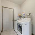 The interior laundry room offers full-size washer and dryer units, shelving, and access to the garage making household routines smooth and convenient.