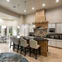 A chef s dream with custom cabinets, granite counters, a statement stone hood, and a cozy dining nook flooded with natural light. This Scottsdale kitchen blends rustic warmth with high-end functionality.