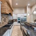 A standout kitchen featuring stainless appliances, double ovens, granite counters, and a dramatic stone range hood. Ample cabinetry and an oversized island complete this Scottsdale chef s dream setup.