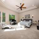 Spacious and bright, the primary suite features tray ceilings, wall-to-wall windows, and neutral tones. This Scottsdale retreat offers comfort and privacy, with plenty of space for a sitting area or workstation.