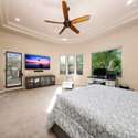 Enjoy direct access to the patio and tranquil garden views from this generously sized bedroom. Ideal for relaxation, the room features custom ceiling details, plush carpet, and space for media or office furniture.