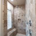 Enjoy a full-body shower experience in this beautifully tiled walk-in shower, featuring multiple shower heads, a built-in bench, and upscale finishes throughout.