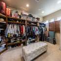 A spacious walk-in closet designed for function and convenience with rich wood shelving, an upholstered bench, and an additional washer/dryer set. Smart living in the heart of Scottsdale.