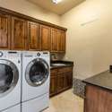 This well-equipped laundry room includes front-load appliances, granite countertops, and plenty of upper and lower cabinetry for storage. A functional and stylish utility space in this upgraded home.