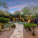 An inviting view of this Scottsdale property s private oasis highlights evening lighting, a lush lawn, and thoughtfully designed outdoor zones for play, rest, and celebration.