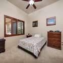 This secondary bedroom features warm wood accents, high ceilings, and plush carpeting. A quiet space in the home ideal for visitors or versatile enough for a nursery or workspace.