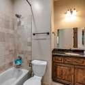 This shared bathroom features rich wood cabinetry, granite countertops, and a tiled shower/tub combo, creating a practical yet elegant solution for connected bedrooms in this spacious Scottsdale home.