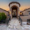 A curved staircase leads to the home s impressive arched front entrance, creating a grand sense of arrival. Flanked by blooming greenery and iron railings, the entryway sets the tone for a Scottsdale home that blends timeless design with sophisticated updates.