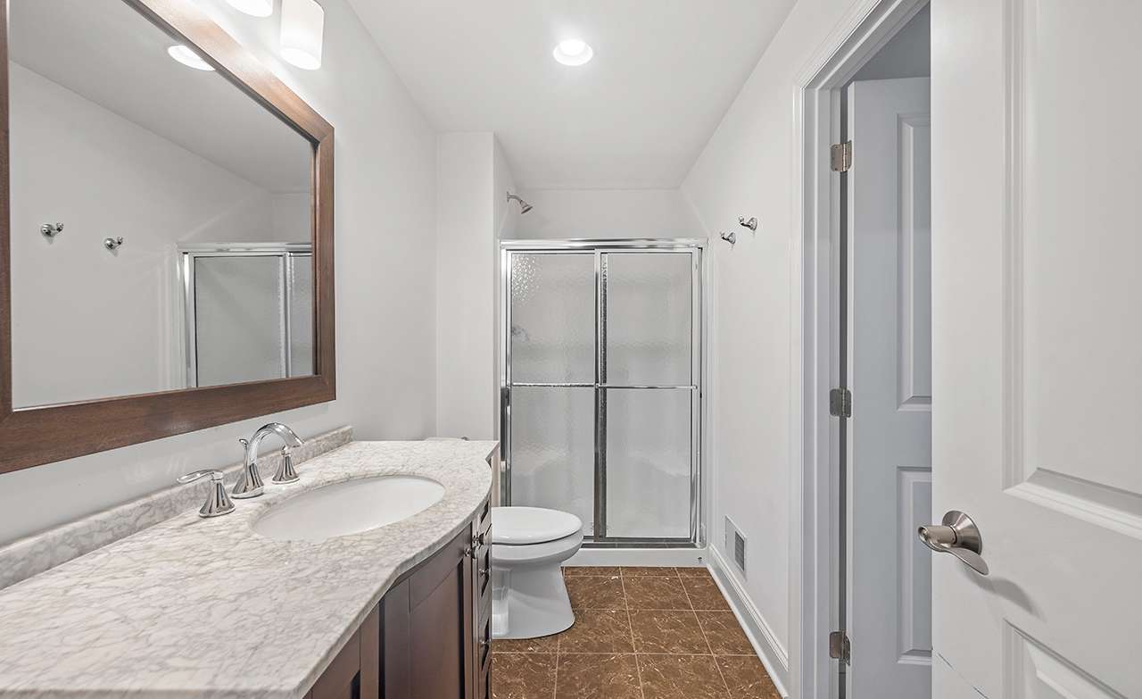 58 of 69. The lower-level full-bath is outfitted with a shower and a granite-topped vanity.