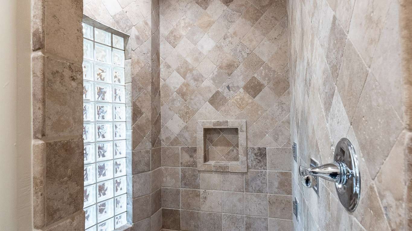17 of 39. Enjoy a full-body shower experience in this beautifully tiled walk-in shower, featuring multiple shower heads, a built-in bench, and upscale finishes throughout.