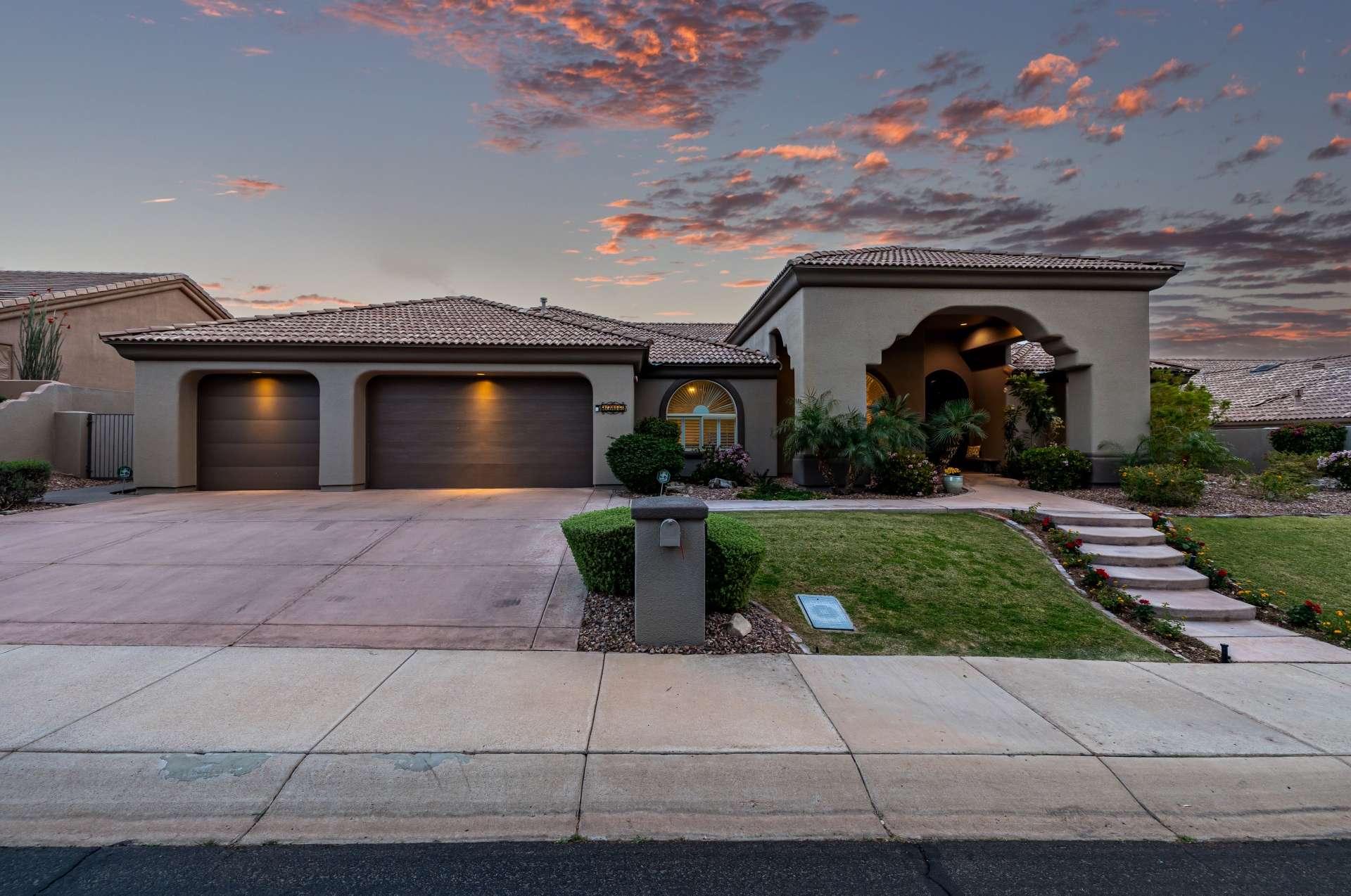 57 of 65. Captured at golden hour, this evening exterior shot highlights the stunning architecture, expansive garage, and manicured front landscaping. A peaceful setting in a prime Arizona location with great walk-up charm.