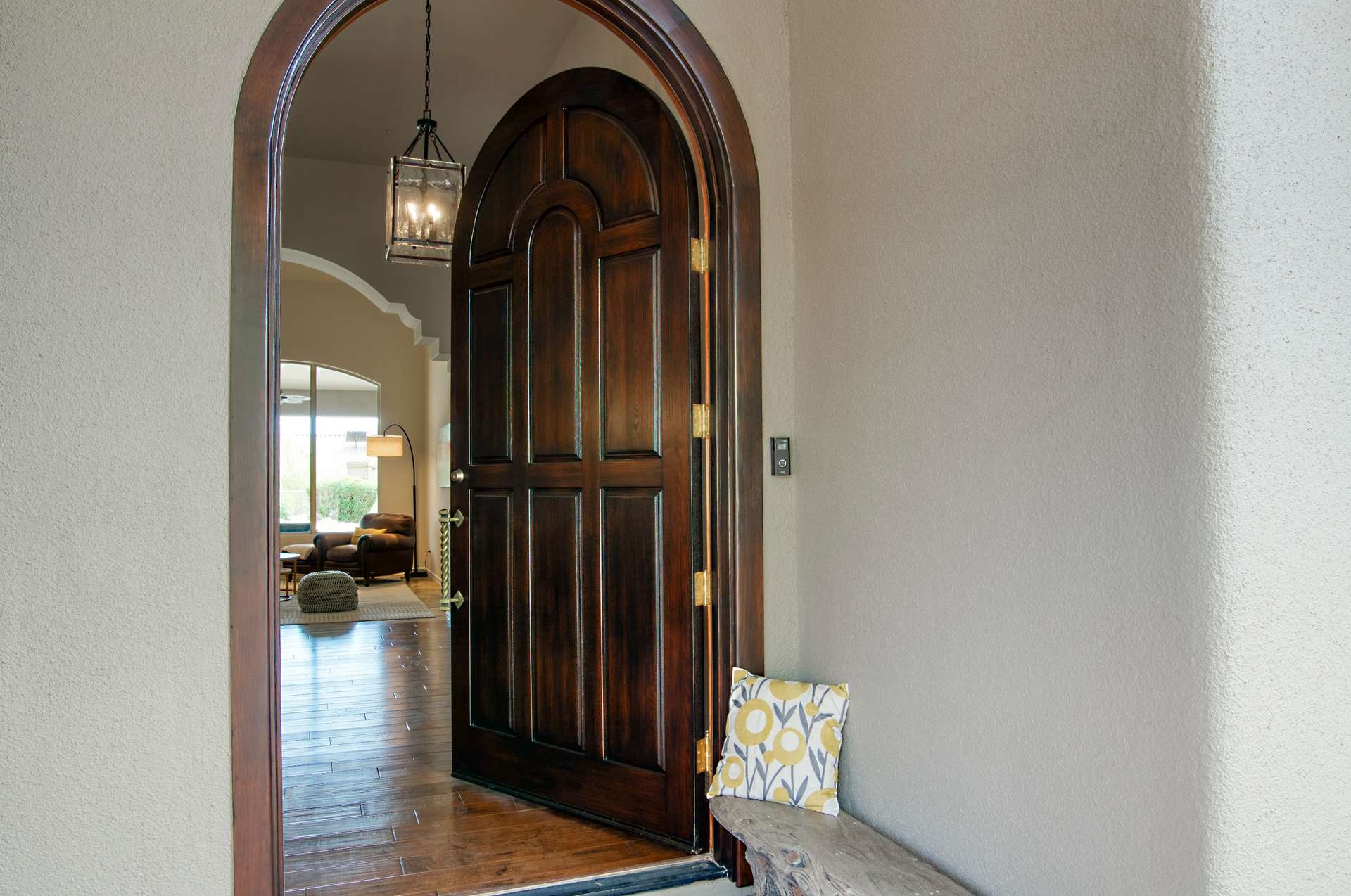 4 of 65. Step into style through a rounded wood door beneath an arched portico. This inviting entryway blends Mediterranean influences with Arizona elegance, setting the tone for the custom design and light-filled interiors found inside.